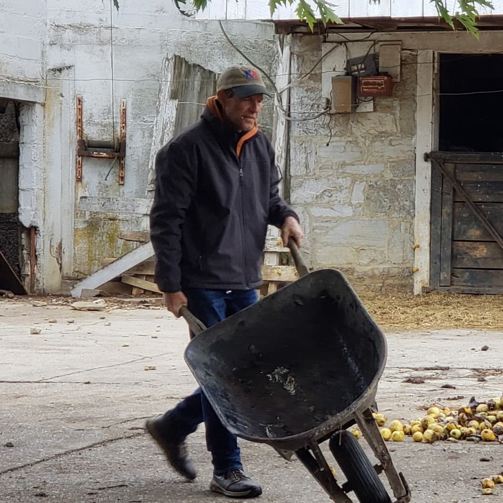Charlie Bill McDonald pushing a wheelbarrow beside the barn at Glencoe Farm